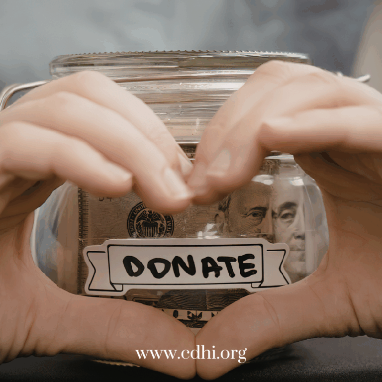 Hands frame a glass donation jar filled with money, with a DONATE label on the front.
