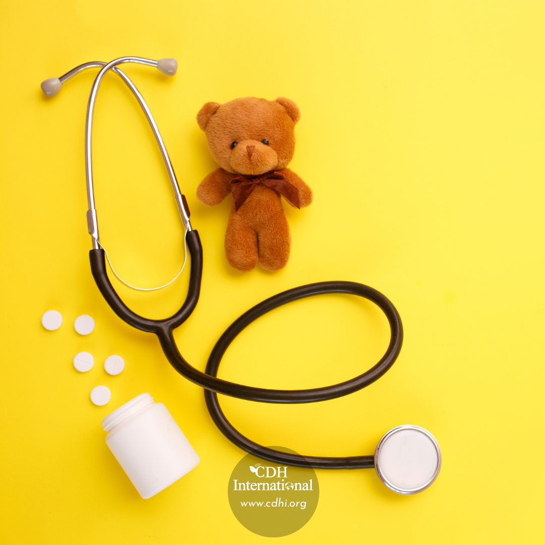 Pediatric medical scene: stethoscope, a brown teddy bear, pills, and a medicine bottle on a bright yellow background.