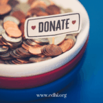 Coin-filled donation jar with a 'DONATE' tag and the website www.cdhi.org visible at the bottom edge.