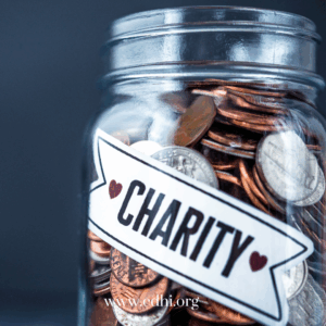 Glass jar filled with coins labeled 'CHARITY' with two heart icons; donation jar for charity, website www.cdhi.org visible on label.