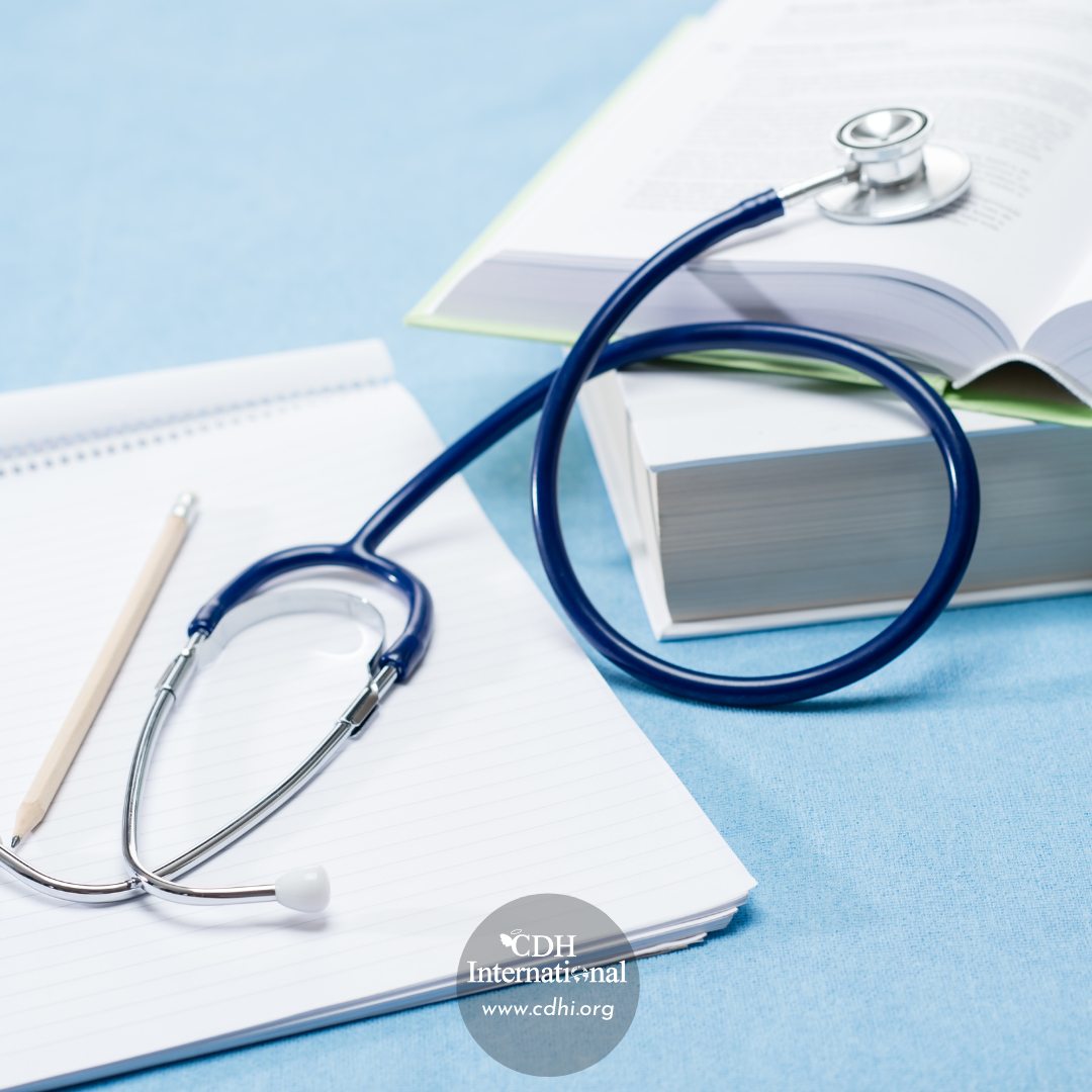 Stethoscope on a lined notebook with a pencil and open medical book, beside a logo watermark (medical study scene).
