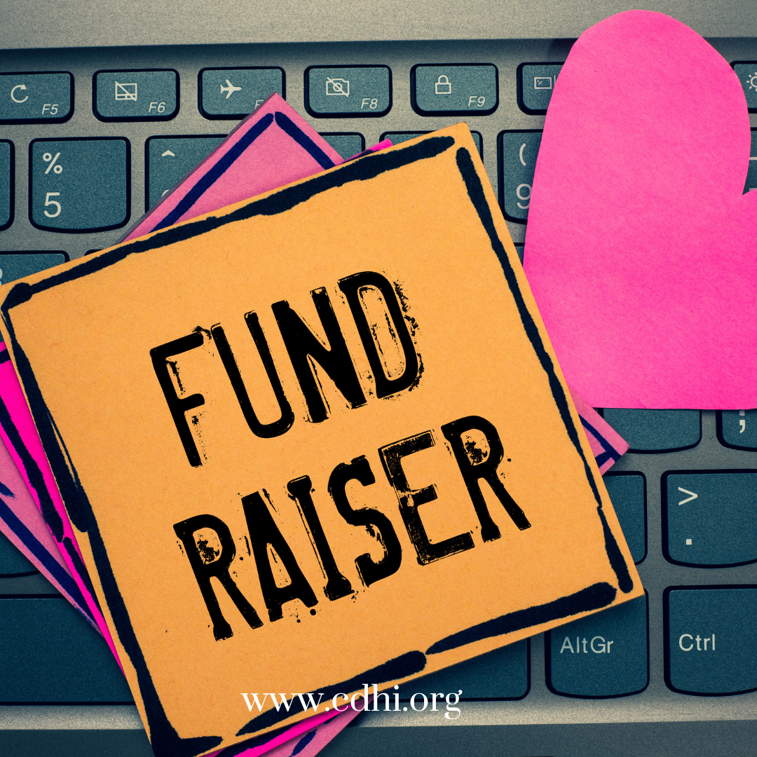 Orange sticky note on a laptop keyboard reading 'FUND RAISER' with pink paper hearts nearby.
