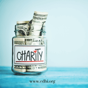 Glass jar filled with rolled dollar bills labeled Charity, with cdhi.org visible at the bottom edge.