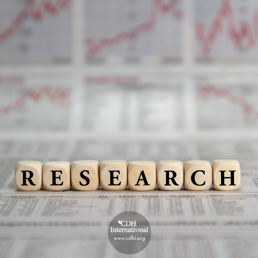 Wooden blocks spell 'RESEARCH' on a desk with blurred financial charts in the background and a CDH International logo at the bottom center.